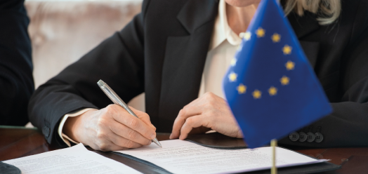femme qui signent un document devant un drapeau européen