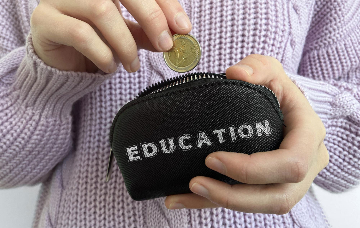 Main de femme mettant une pièce de monnaie dans un portefeuille avec le mot éducation.