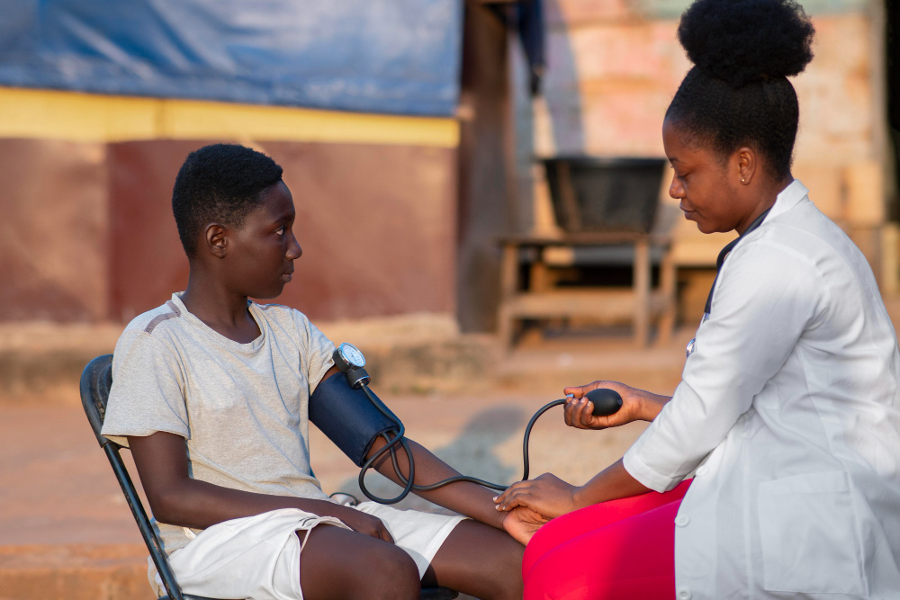 Une femme médecin vérifie la tension artérielle d'un garçon en Afrique.