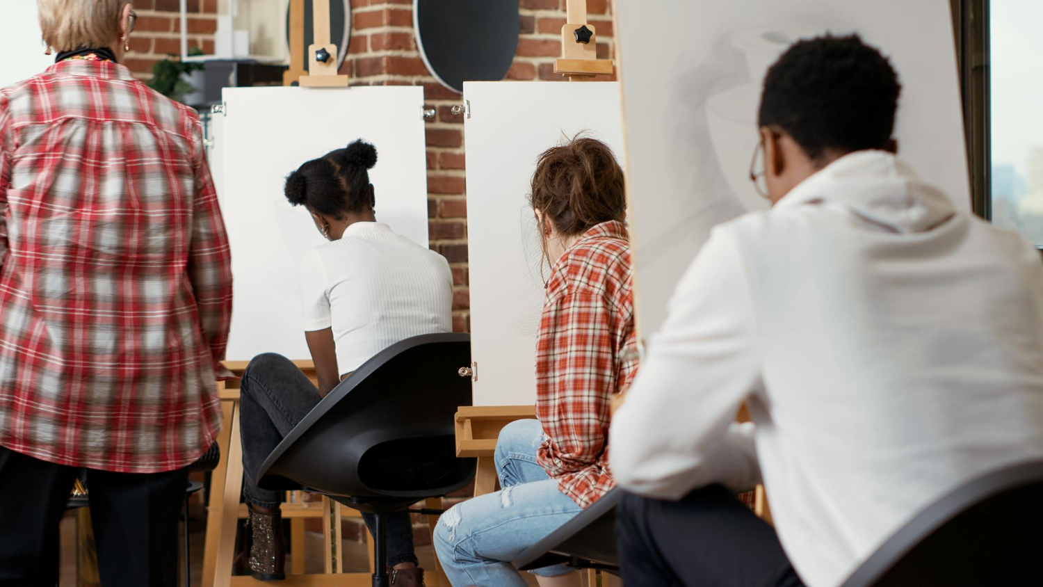 Un groupe de personnes dans un atelier d'art. Ils dessinent sur des toiles.