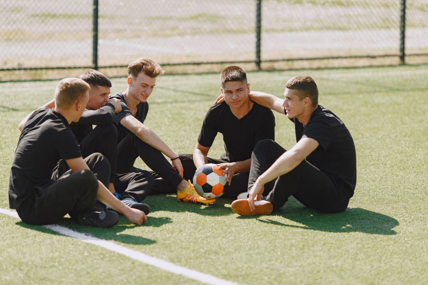 Groupe de footballeurs assis sur la pelouse en train de discuter.