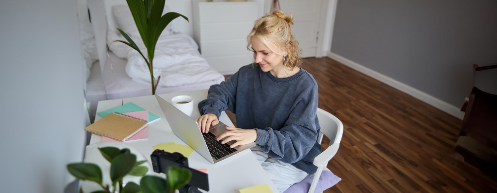 Etudiante assise à son bureau dans sa chambre.