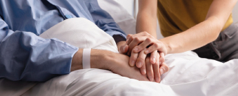 Une femme tenant la main de son mari dans un lit d'hôpital.