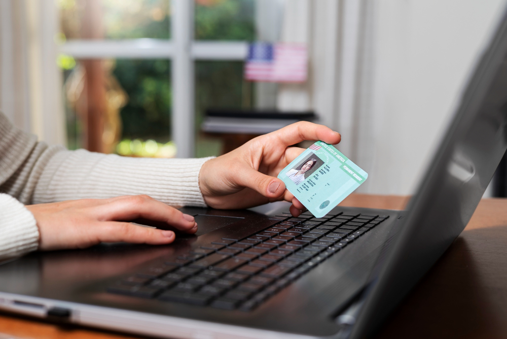 Un homme tenant sa carte d'identité devant un ordintauer.