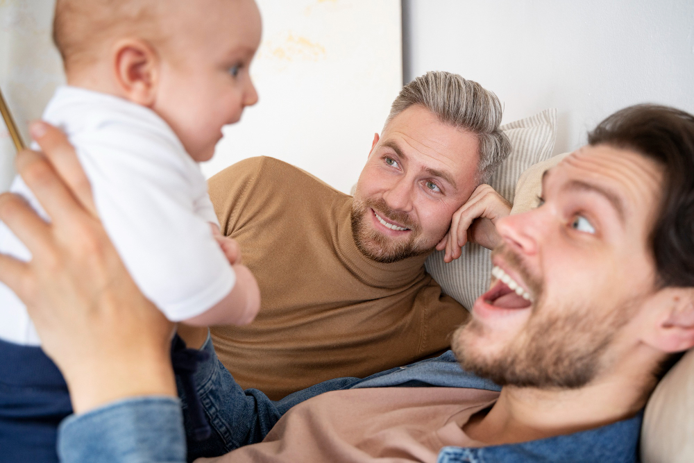 Un couple d'hommes souriant avec un bébé dans les bras.