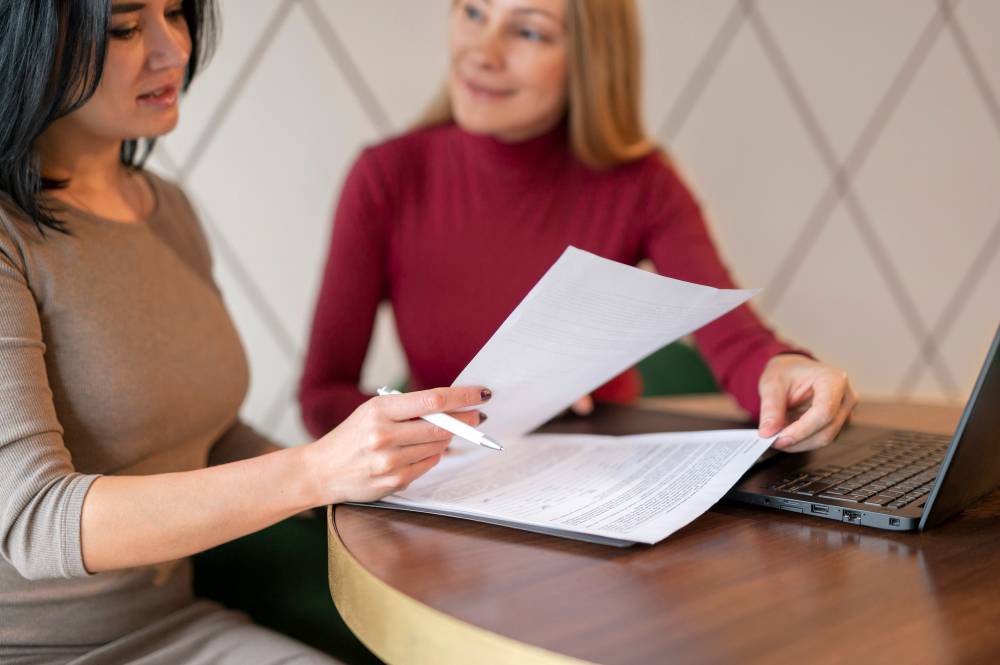 Femmes d'affaire qui discutent ensemble autour de documents posés sur une table.