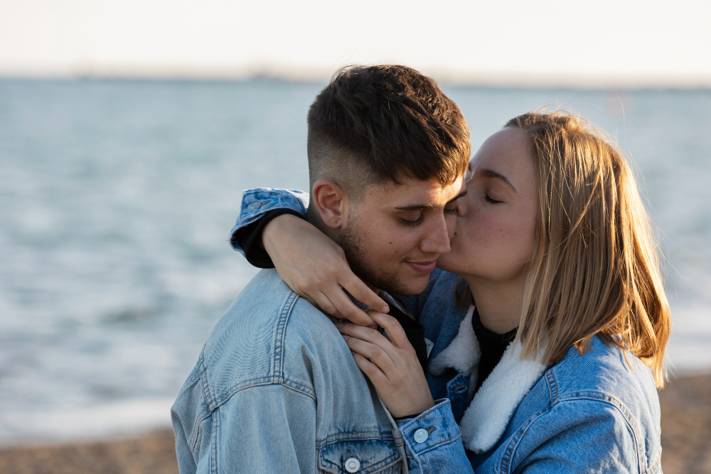 Jeune couple s'embrassant devant la mer.