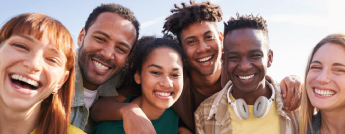 Un groupe de jeunes souriants, de différentes origines posent ensemble.