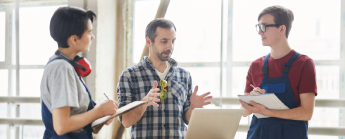 Equipe d'étudiants charpentiers en apprentissage discutant sur un projet.