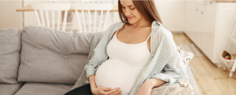 Femme enceinte installée sur un canapé.