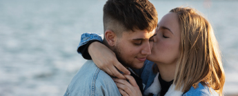 Jeune couple s'embrassant devant la mer.